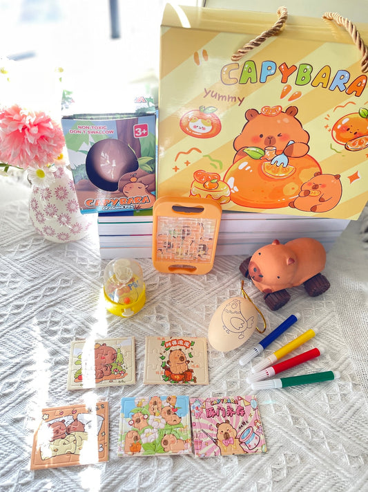 Party bag activity set contents laid out with squishy toy, growing pet egg, DIY painting egg, pocket hoops, puzzles, palm maze and gift bag